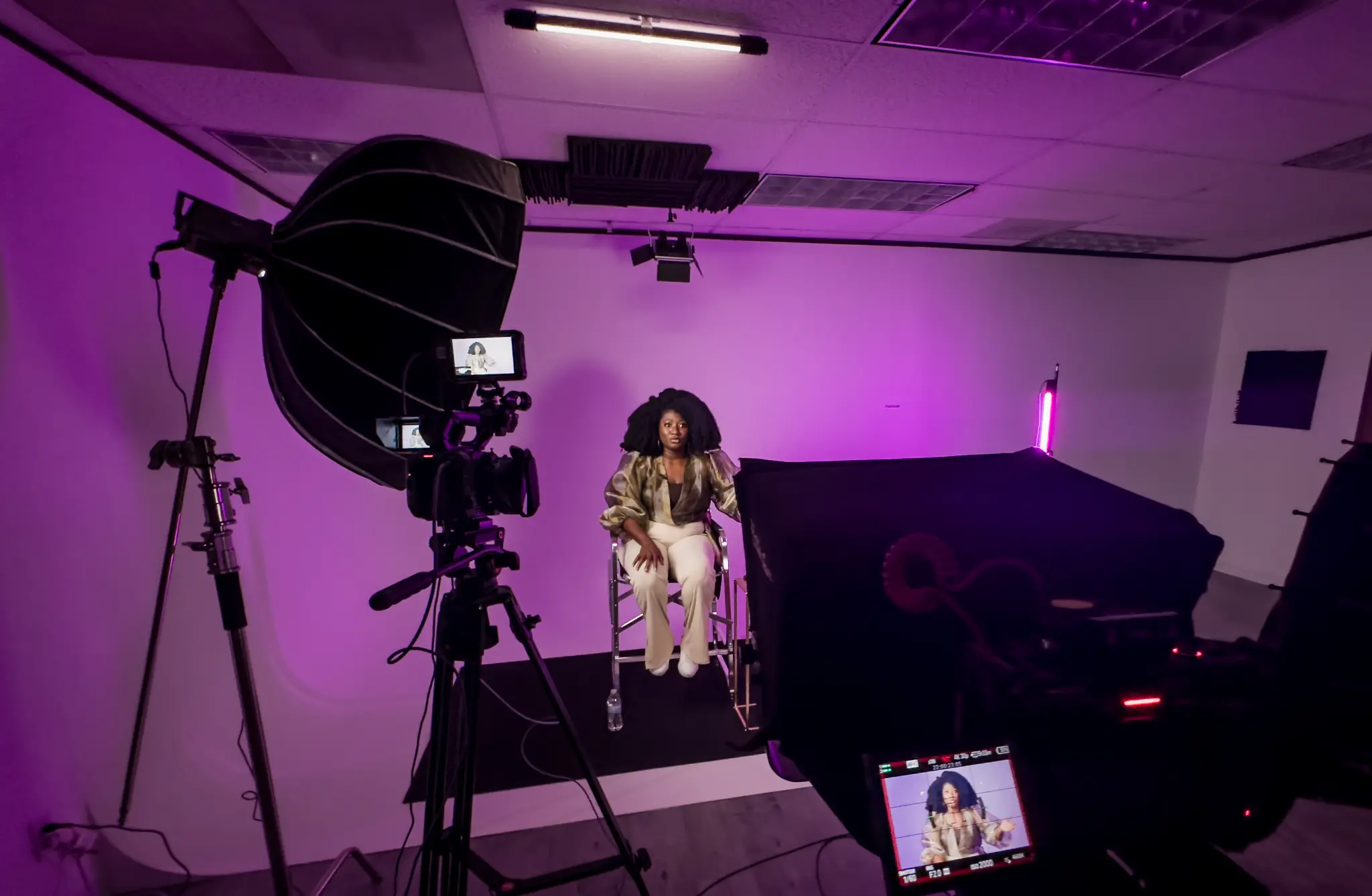 Fokus studio: client on camera under purple LED lighting with softbox and tripod-mounted camera